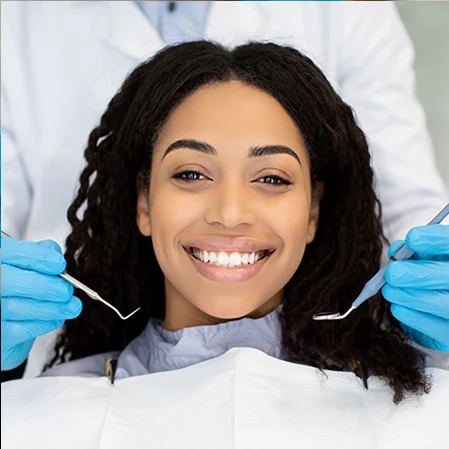 A young woman receiving cosmetic dentistry services. She smiles with bright white teeth.