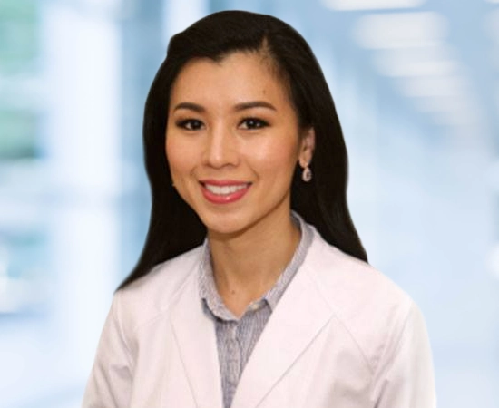 Dentist Dallas TX Nhu Dang HP About Dr. Nhu Dang from Bella Family Dental wearing a white coat and smiling during a professional photoshoot